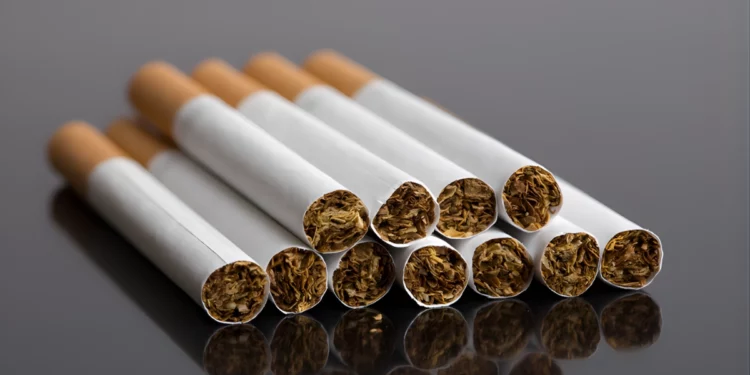 A close-up of a hand holding a lit cigarette, representing South Africa's illicit cigarette market.