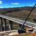 A long concrete bridge spans a river valley in the Mokhotlong highlands of Lesotho, with dignitaries gathered for an official opening ceremony.