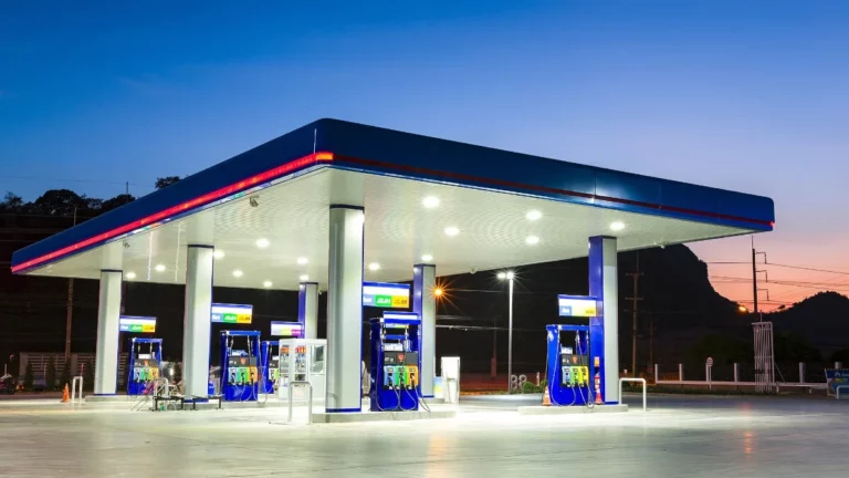 A South African petrol station forecourt at night with overhead lights illuminating empty fuel pumps and a vacant attendant island.
