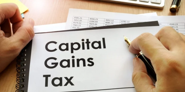 A person calculating figures on a laptop with South African rand notes and a SARS tax form on the desk