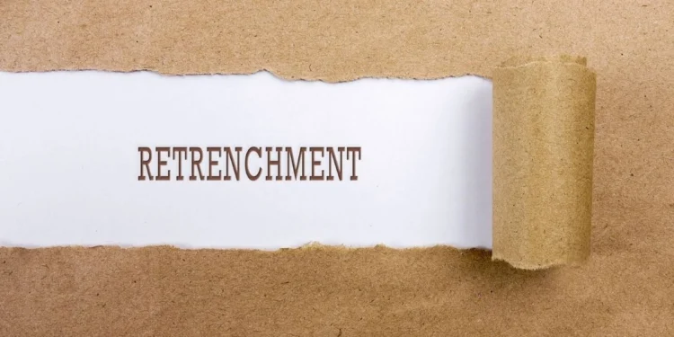 A worker reads a retrenchment notice letter at a desk in an office