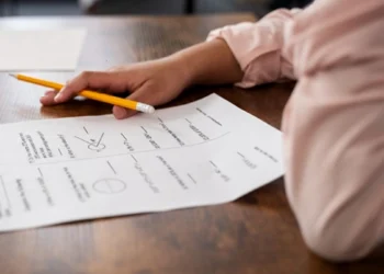 A young adult sitting at a desk with matric study guides and past exam papers