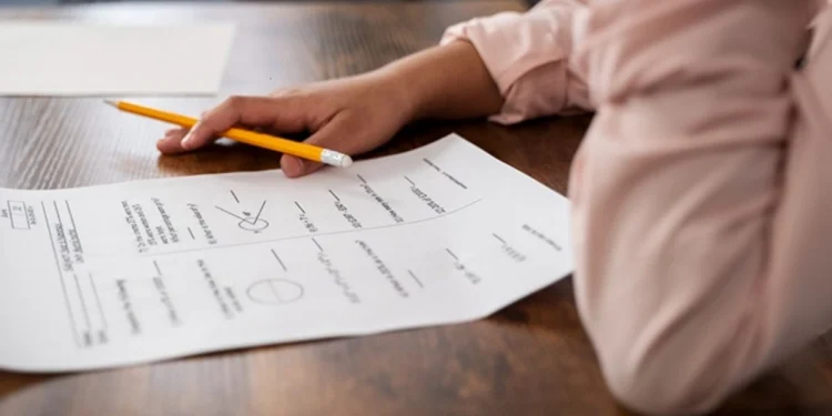 A young adult sitting at a desk with matric study guides and past exam papers