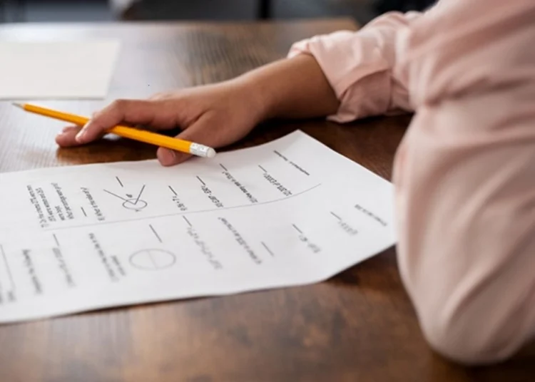 A young adult sitting at a desk with matric study guides and past exam papers