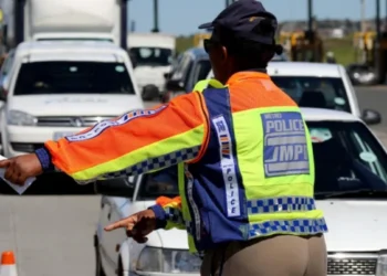 A traffic officer at a roadside checkpoint writing out an infringement notice for a driver in South Africa