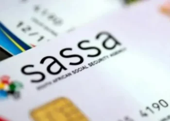 An older woman waiting in a queue outside a SASSA local office in South Africa with her identity document in hand