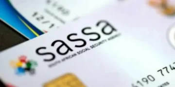 An older woman waiting in a queue outside a SASSA local office in South Africa with her identity document in hand