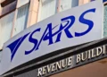 A person at a kitchen table going through tax paperwork and a laptop showing the SARS eFiling login screen