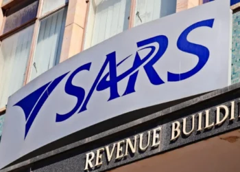 A person at a kitchen table going through tax paperwork and a laptop showing the SARS eFiling login screen