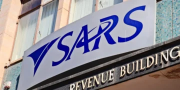 A person at a kitchen table going through tax paperwork and a laptop showing the SARS eFiling login screen