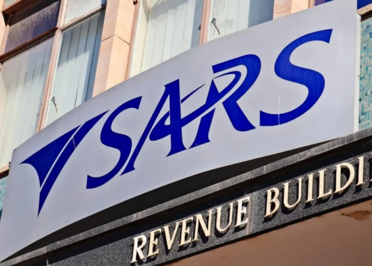 A person at a kitchen table going through tax paperwork and a laptop showing the SARS eFiling login screen