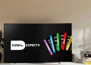 A DStv decoder and remote in front of a television showing a sports broadcast in a South African living room