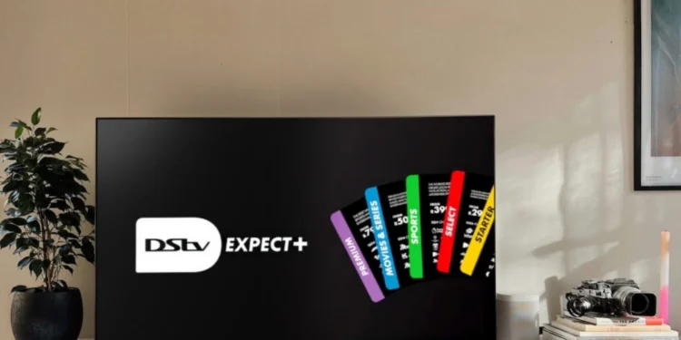 A DStv decoder and remote in front of a television showing a sports broadcast in a South African living room