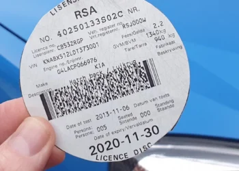 A vehicle licence disc displayed on a car windscreen in Johannesburg with traffic in the background