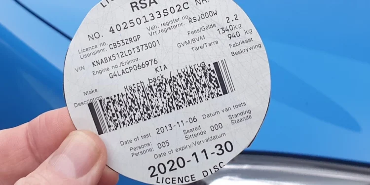 A vehicle licence disc displayed on a car windscreen in Johannesburg with traffic in the background