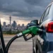 A fuel attendant filling a car at a South African petrol station with the price board visible behind