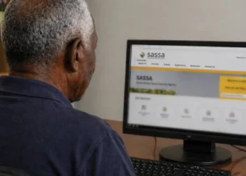 An older woman using a smartphone outside a SASSA office in South Africa