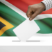 A voter marks a ballot paper behind a cardboard voting booth at a South African voting station