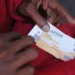 A queue of grant beneficiaries waiting outside a SASSA local office with identity documents in hand