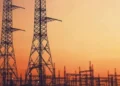High voltage transmission lines running past a coal-fired power station cooling tower in South Africa