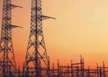 High voltage transmission lines running past a coal-fired power station cooling tower in South Africa