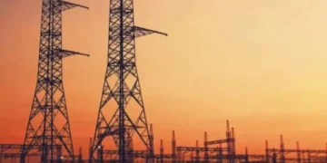 High voltage transmission lines running past a coal-fired power station cooling tower in South Africa