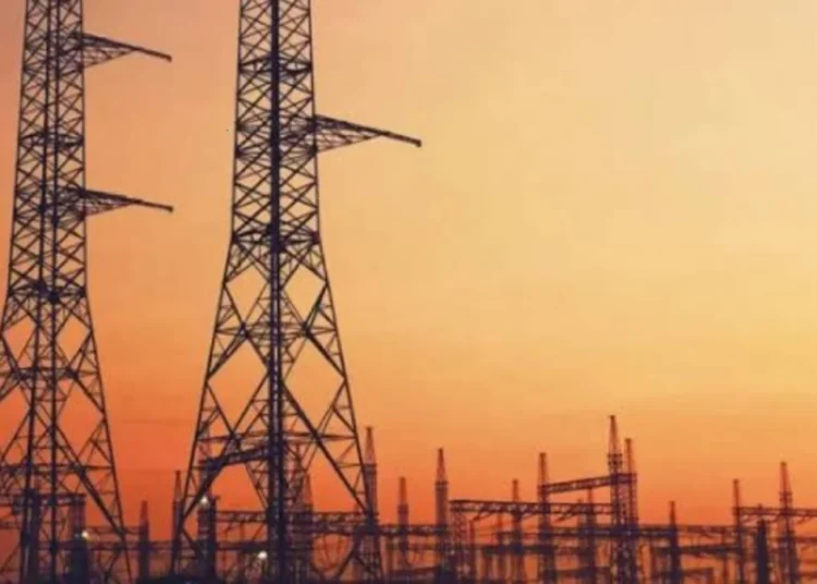 High voltage transmission lines running past a coal-fired power station cooling tower in South Africa