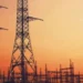 High voltage transmission lines running past a coal-fired power station cooling tower in South Africa