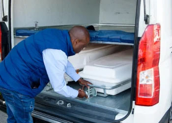 A coffin being loaded into the cargo hold of an aircraft at a South African airport