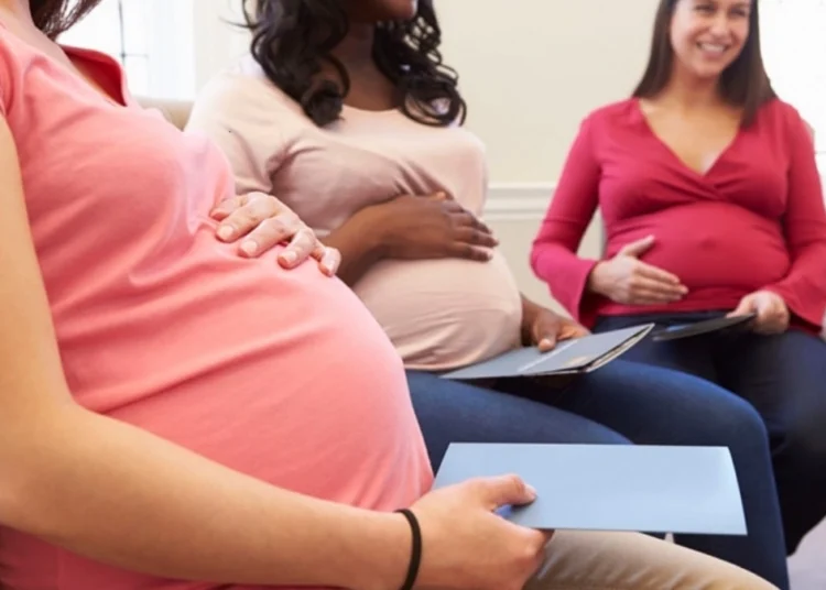 A pregnant woman filling in a UIF maternity benefit application form at a desk