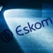 Eskom technicians working on a pole-mounted transformer above a township street
