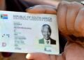 A Home Affairs official handing a Smart ID card to a young applicant at a service counter