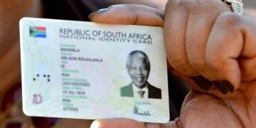 A Home Affairs official handing a Smart ID card to a young applicant at a service counter